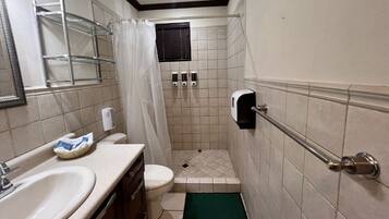 Un baño con lavamanos, inodoro, ducha y secamanos.