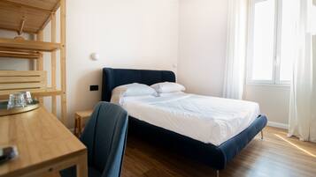 A bedroom with a bed, a desk, and a chair.