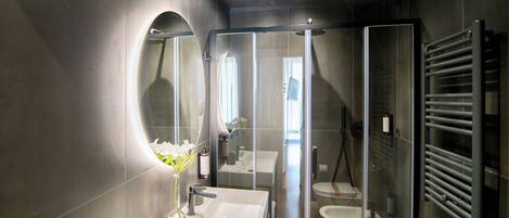 A modern bathroom with a large mirror, a white sink, and a glass shower enclosure.