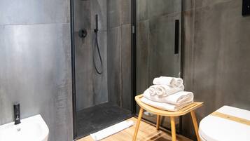 A modern bathroom with a shower, a sink, and a toilet.