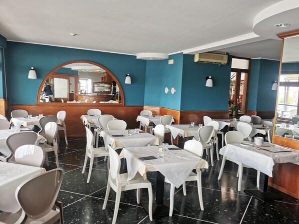 A restaurant with white tables and chairs, a blue wall, and a wooden counter.