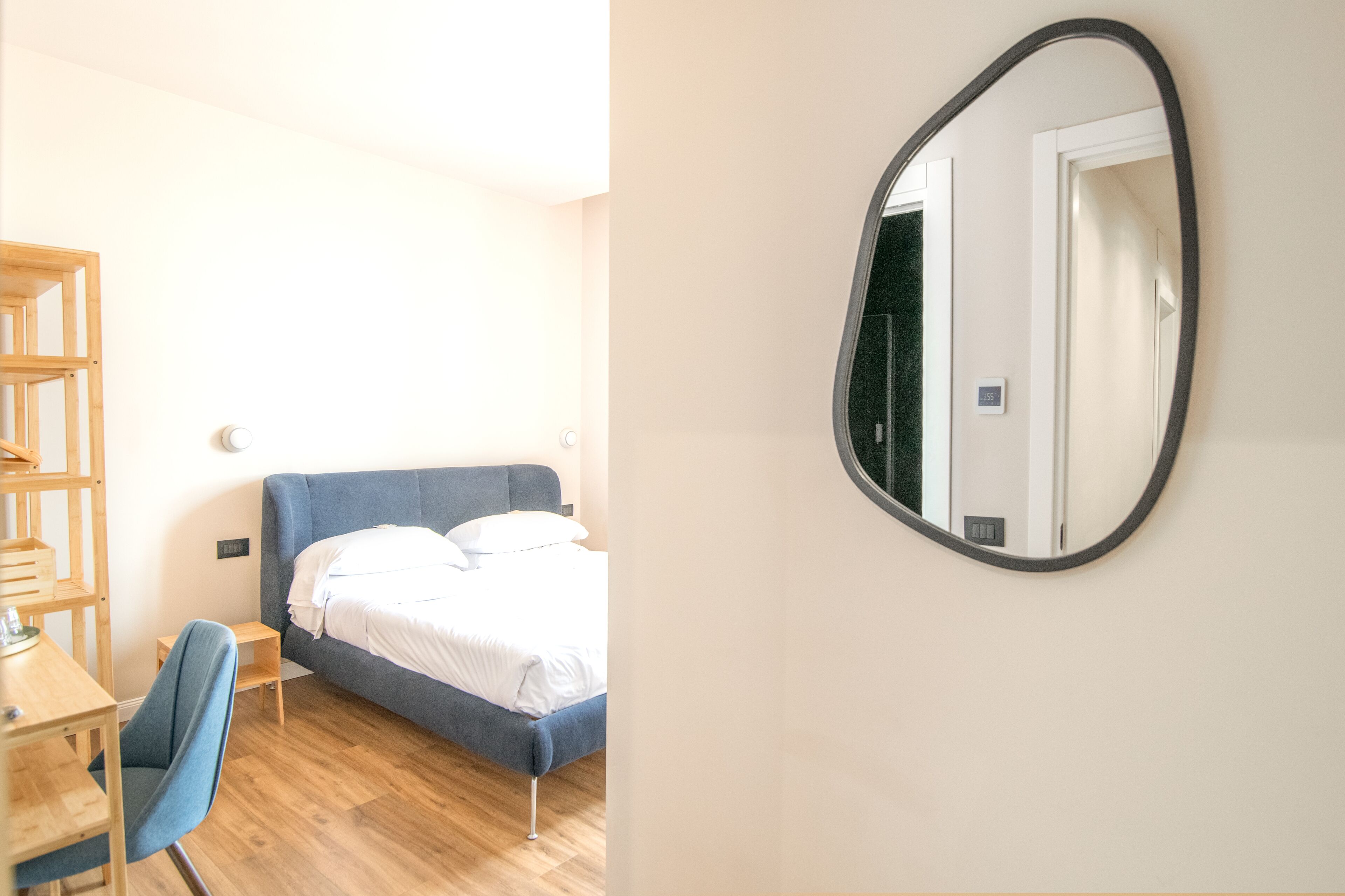 Een slaapkamer met een bed, een bureau, een stoel en een spiegel aan de muur.