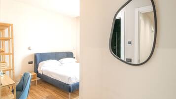 Een slaapkamer met een bed, een bureau, een stoel en een spiegel aan de muur.