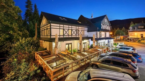 Un edificio tradicional de entramado de madera con un área de estar al aire libre cubierta y un estacionamiento.