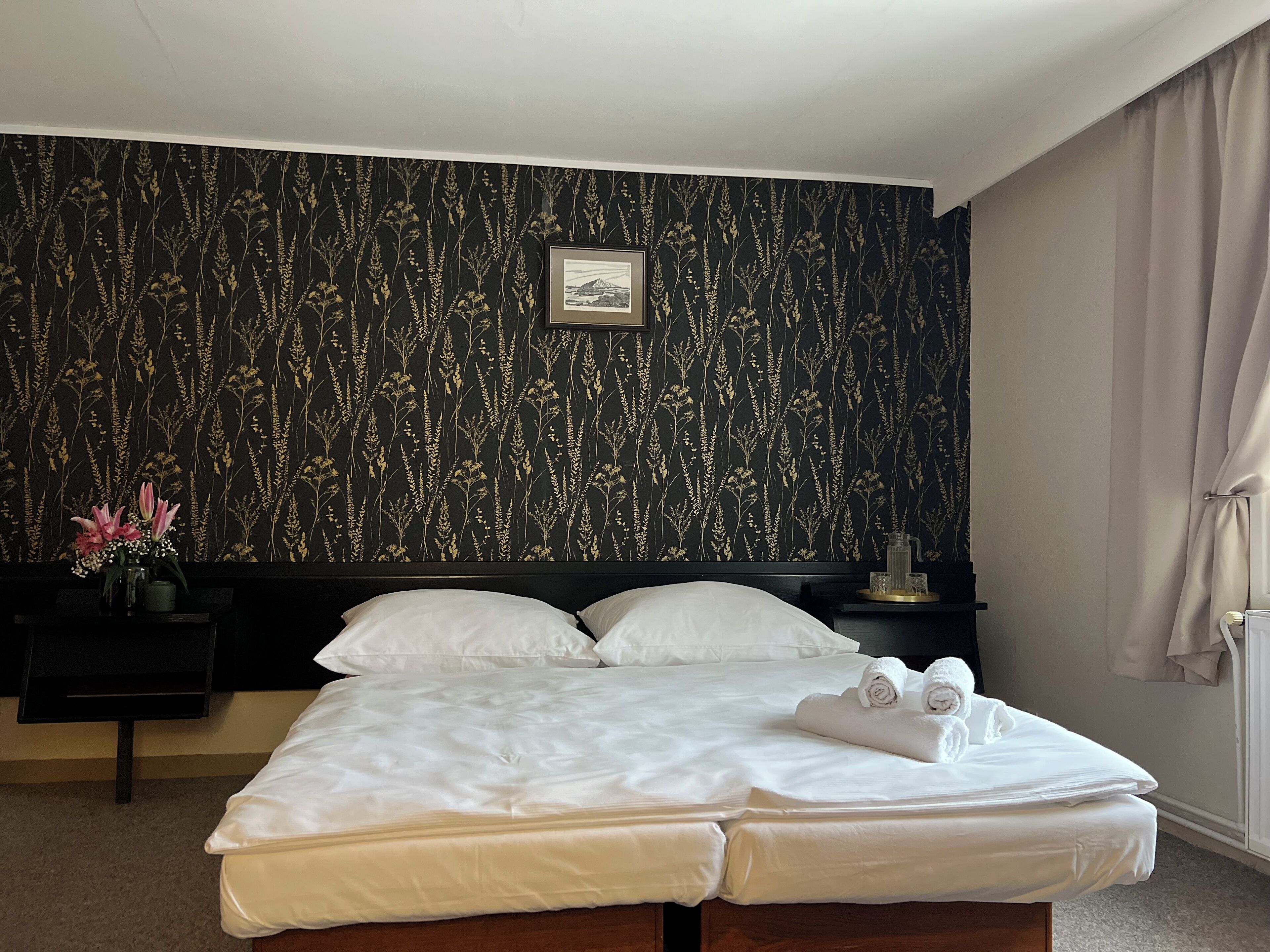 Habitación de hotel con una cama grande, una mesita de noche con lámpara y un cuadro en la pared.