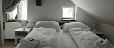 A twin room with two beds, a window, a desk, and a lamp.