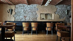 Un interior rústico con techos de ladrillo visto, paredes de piedra y sillas estampadas.