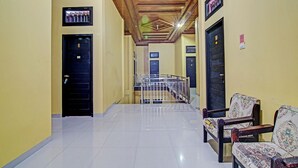 A hotel hallway with a wooden ceiling, numbered doors, and a metal railing leading to an elevator. - Hotel O Arafah Homestay Syariah Near Badan Pertanahan Nasional - Kantor Pertanahan Kabupaten Kampa (Bangkinang)