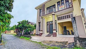 A two-story building with a balcony, a front entrance, and a parked motorcycle. - Hotel O Arafah Homestay Syariah Near Badan Pertanahan Nasional - Kantor Pertanahan Kabupaten Kampa (Bangkinang)
