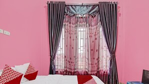 A bedroom with a bed, pink walls, and a window with curtains. - Hotel O Arafah Homestay Syariah Near Badan Pertanahan Nasional - Kantor Pertanahan Kabupaten Kampa (Bangkinang)