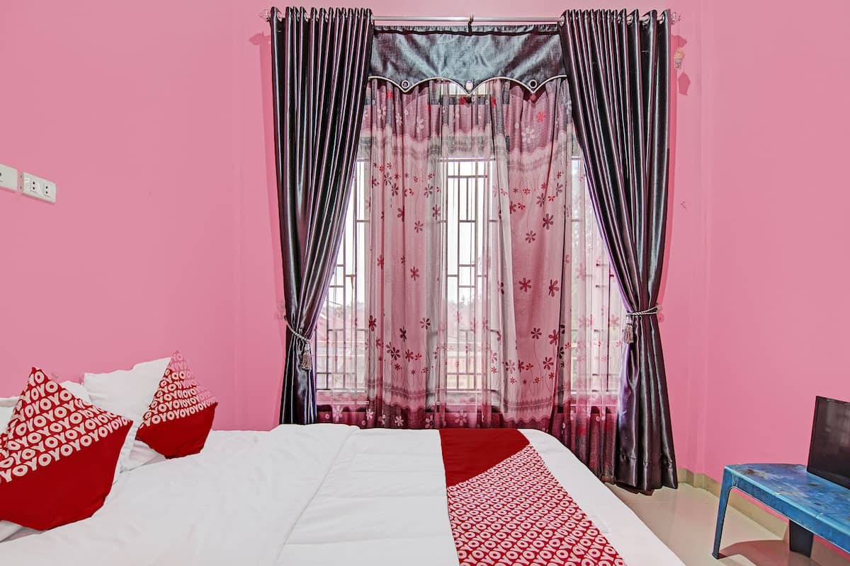 Un dormitorio con cama, paredes rosas y una ventana con cortinas.