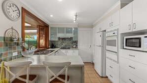 Una cocina moderna con armarios blancos, microondas integrado y una isla grande con taburetes de bar.