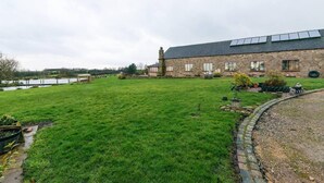 Ein Steinhaus mit einem großen Rasen und einem Teich.