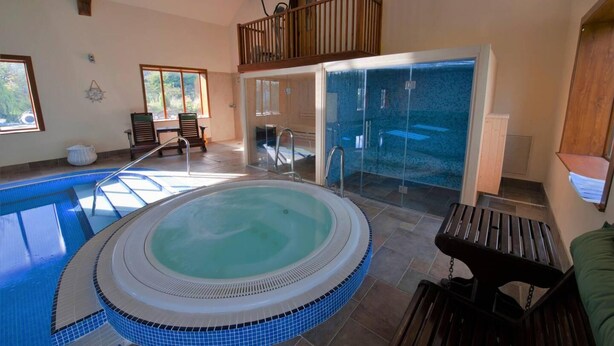 Ein Whirlpool in einem Raum mit Balkon, Fenster und Zugang zu einem Duschbereich.