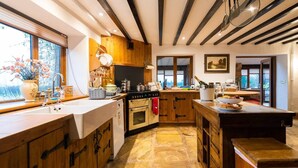 A kitchen with wooden cabinets, a stove, and a large window. - Lakeside Escape, Stone Countryside Cottage (Leek)