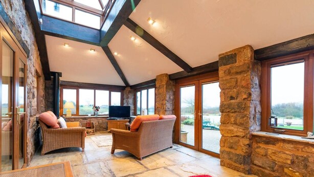 A spacious room with stone walls, large windows, and a high ceiling. - Lakeside Escape, Stone Countryside Cottage (Leek)