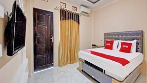 Habitación de hotel con cama, televisión, puerta y aire acondicionado.