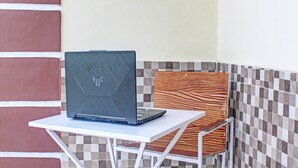 Una computadora portátil sobre una mesa blanca con un muro de azulejos a cuadros al fondo.