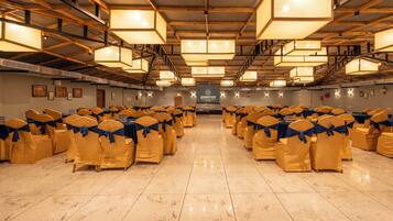 A large hall with rows of tables and chairs, each with yellow chairs and blue sashes.