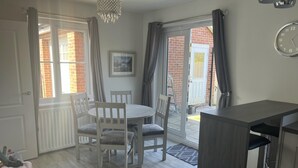 A kitchen with a dining table, chairs, a small cabinet, and a clock on the wall. - Remarkable 3-bed House in Wirral (Wirral)