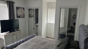 A bedroom with a bed, a TV, a dresser, and a mirror. - Remarkable 3-bed House in Wirral (Wirral)