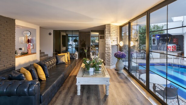 A modern living room with a black leather sofa, a white coffee table, and a large window overlooking a pool. - Azuu Bohem (Antalya)