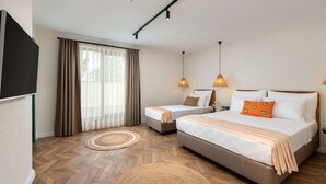 A hotel room with a large bed, a smaller bed, a TV, and a window with curtains. - Azuu Bohem (Antalya)