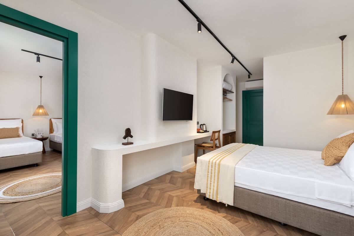 A modern bedroom with a bed, a desk, and a TV.