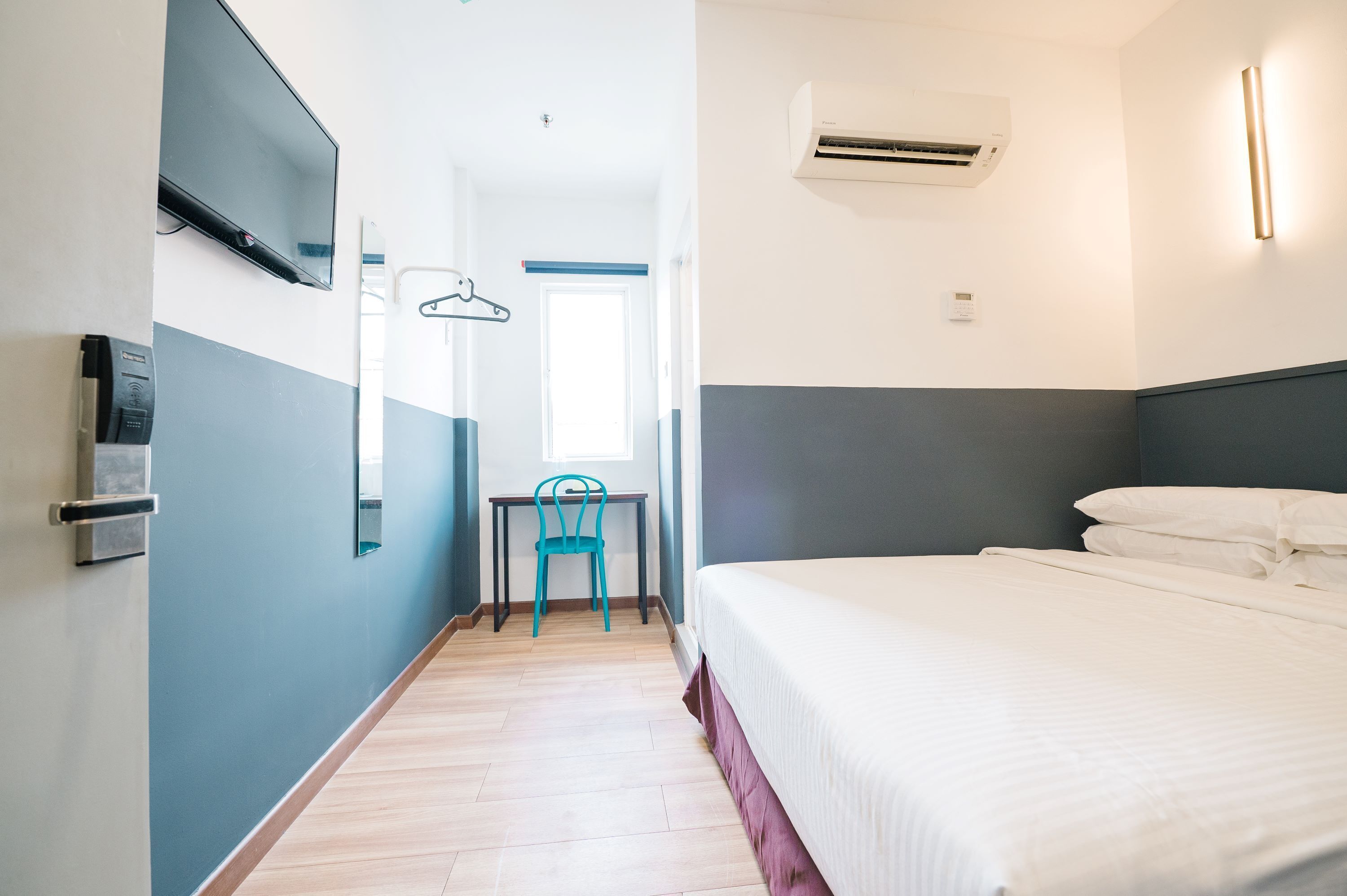 Una habitación de hotel con una cama, un escritorio, una silla, un televisor y un equipo de aire acondicionado.