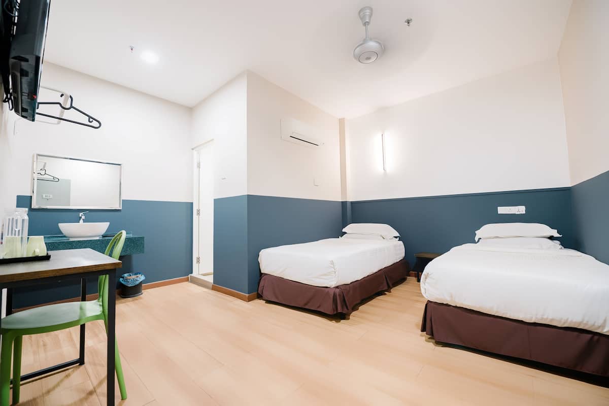Hotellihuone, jossa on kaksi sänkyä, työpöytä tuolilla, televisio, peili ja ikkuna.