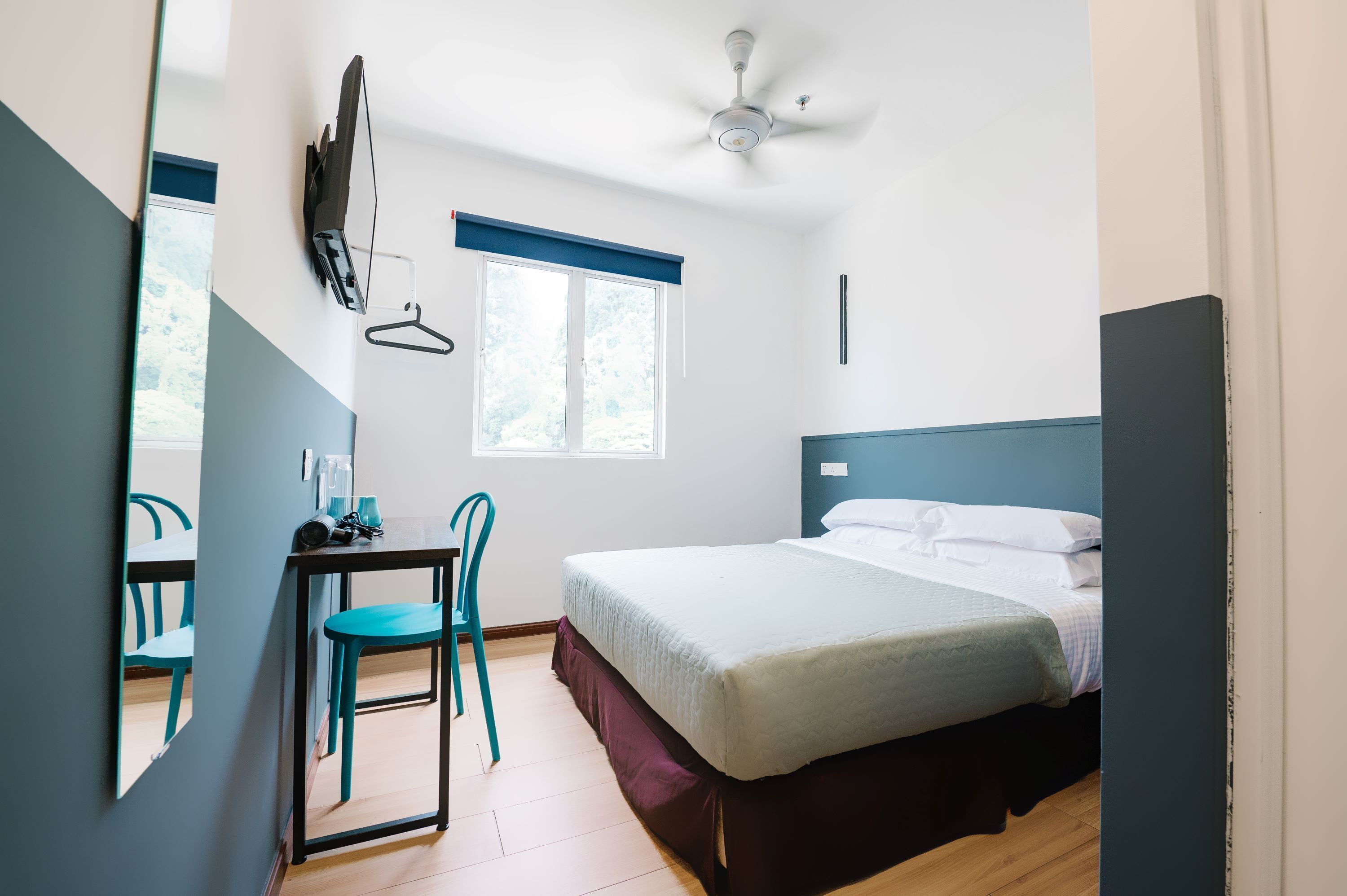 Una camera da letto con un letto, una scrivania, una sedia, un ventilatore a soffitto e una finestra.