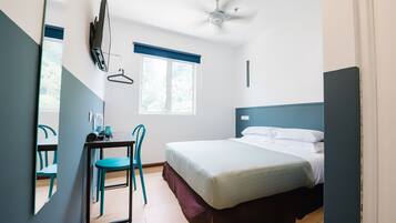 Una camera da letto con un letto, una scrivania, una sedia, un ventilatore a soffitto e una finestra.