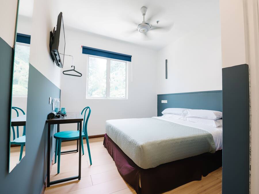 Una camera da letto con un letto, una scrivania, una sedia, un ventilatore a soffitto e una finestra.