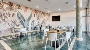 Un comedor moderno con un mural grande, suelo de mármol y sillas blancas.