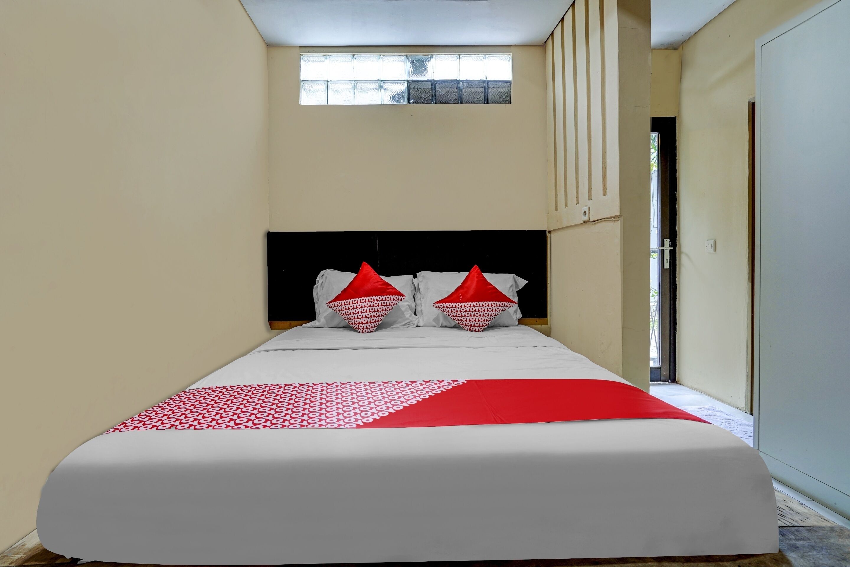 A bed with a white and red bedspread, two red pillows, and a black headboard.