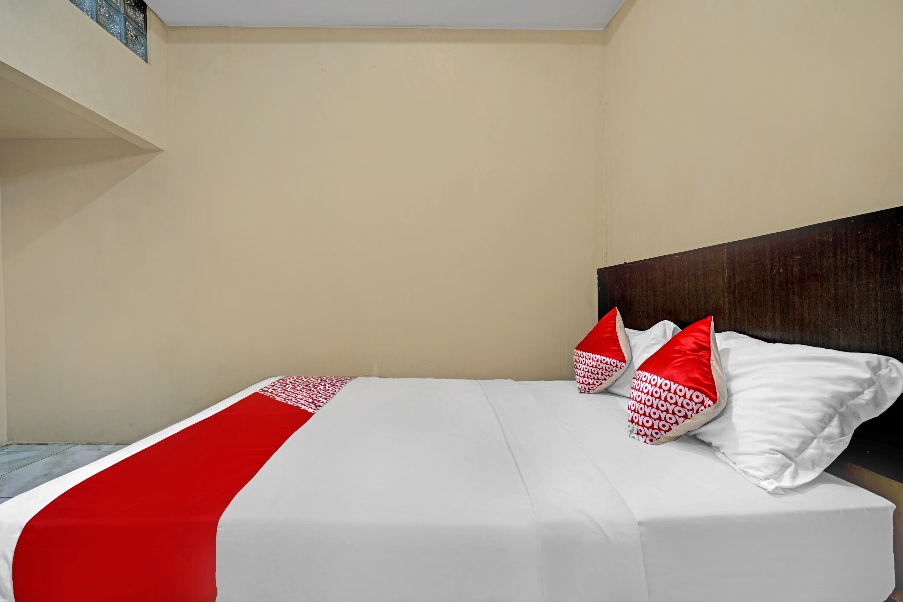 Ein Hotelzimmer mit einem Bett, weißer Bettwäsche und roten Kissen.