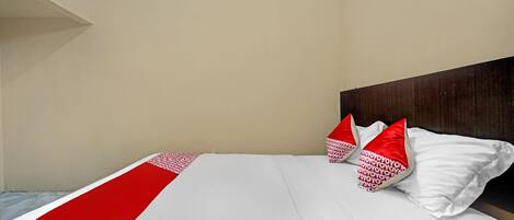 Una habitación de hotel con cama, ropa de cama blanca y almohadas rojas.