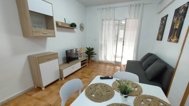 Ein modernes Wohnzimmer mit Fernseher, Sofa und Esstisch.