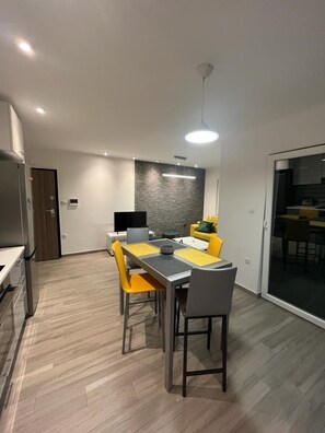 A modern kitchen with a dining area, featuring a grey countertop, yellow chairs, and a grey table.
