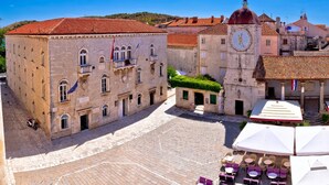 A historic square with cobblestone pavement, a prominent clock tower, and traditional buildings with balconies. - A1 apt With Balcony and sea View, 3 min to Beach (Trogir)