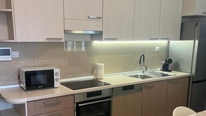 A modern kitchen with light wood cabinets, a built-in microwave, oven, and dishwasher. - A1 apt With Balcony and sea View, 3 min to Beach (Trogir)