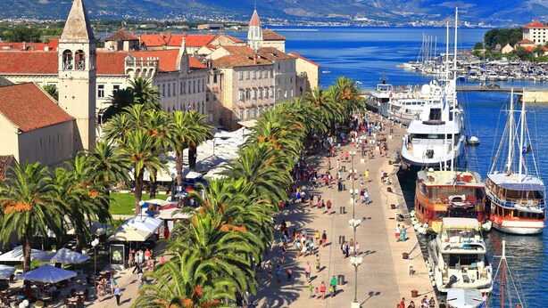 A coastal promenade lined with palm trees and historic buildings, leading to a marina with boats. - A1 apt With Balcony and sea View, 3 min to Beach (Trogir)