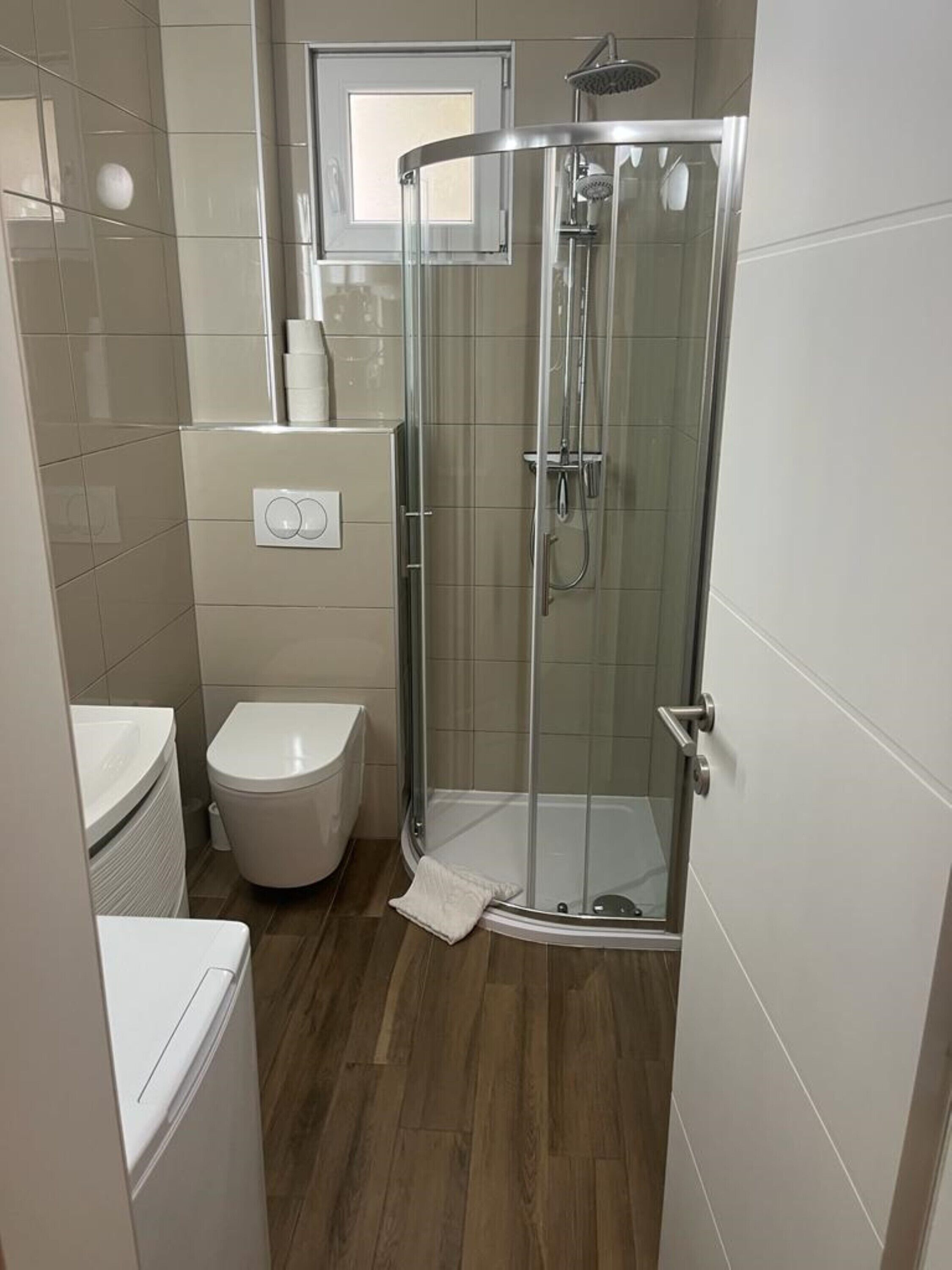 Et moderne badeværelse med bruseniche, toilet og håndvask.