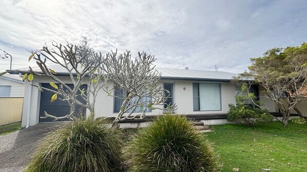 A modern two-story house with a flat roof, large windows, and a well-maintained lawn.