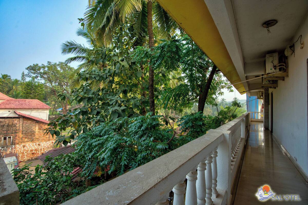 Ein Balkon mit Blick auf einen Garten und ein Gebäude mit rotem Dach.
