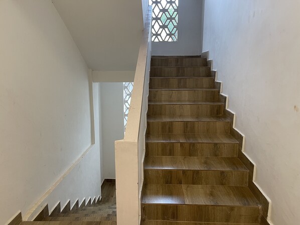 Una escalera de madera con paredes blancas y un diseño geométrico en la ventana.