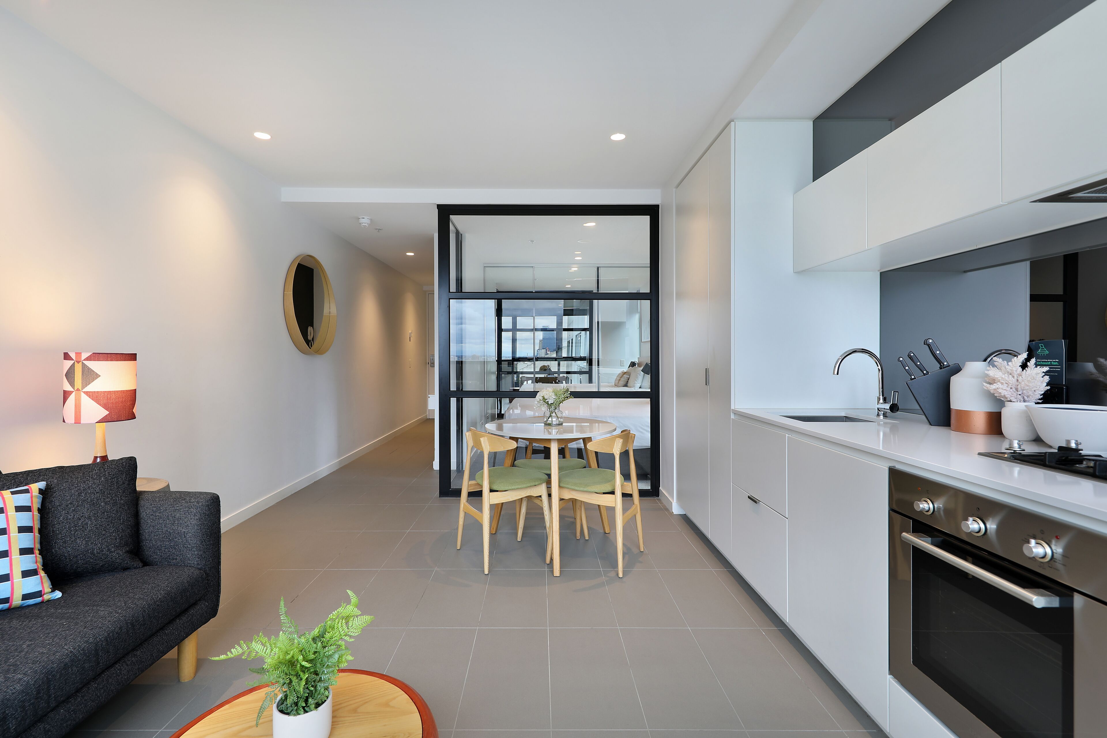 A modern kitchen with a dining area, a sofa, and a lamp.