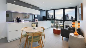 Una cucina moderna con mobili bianchi, un'area pranzo con un tavolo rotondo e sedie, e un'ampia finestra che offre vista sulla città.