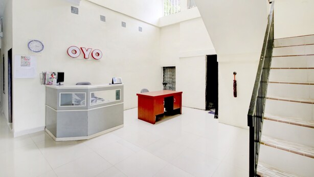 A spacious, modern interior with a reception desk, a red accent desk, and a visible staircase.