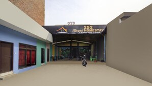 A building entrance with a sign for '252 Royal Homestay' and a motorcycle parked in front.